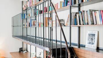 A spiral staircase with metal railings leading to a bookshelf filled with books.