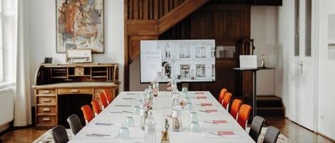 Ein Konferenzraum mit langem Tisch, Stühlen, Wasserflaschen und einer Whiteboard-Tafel.