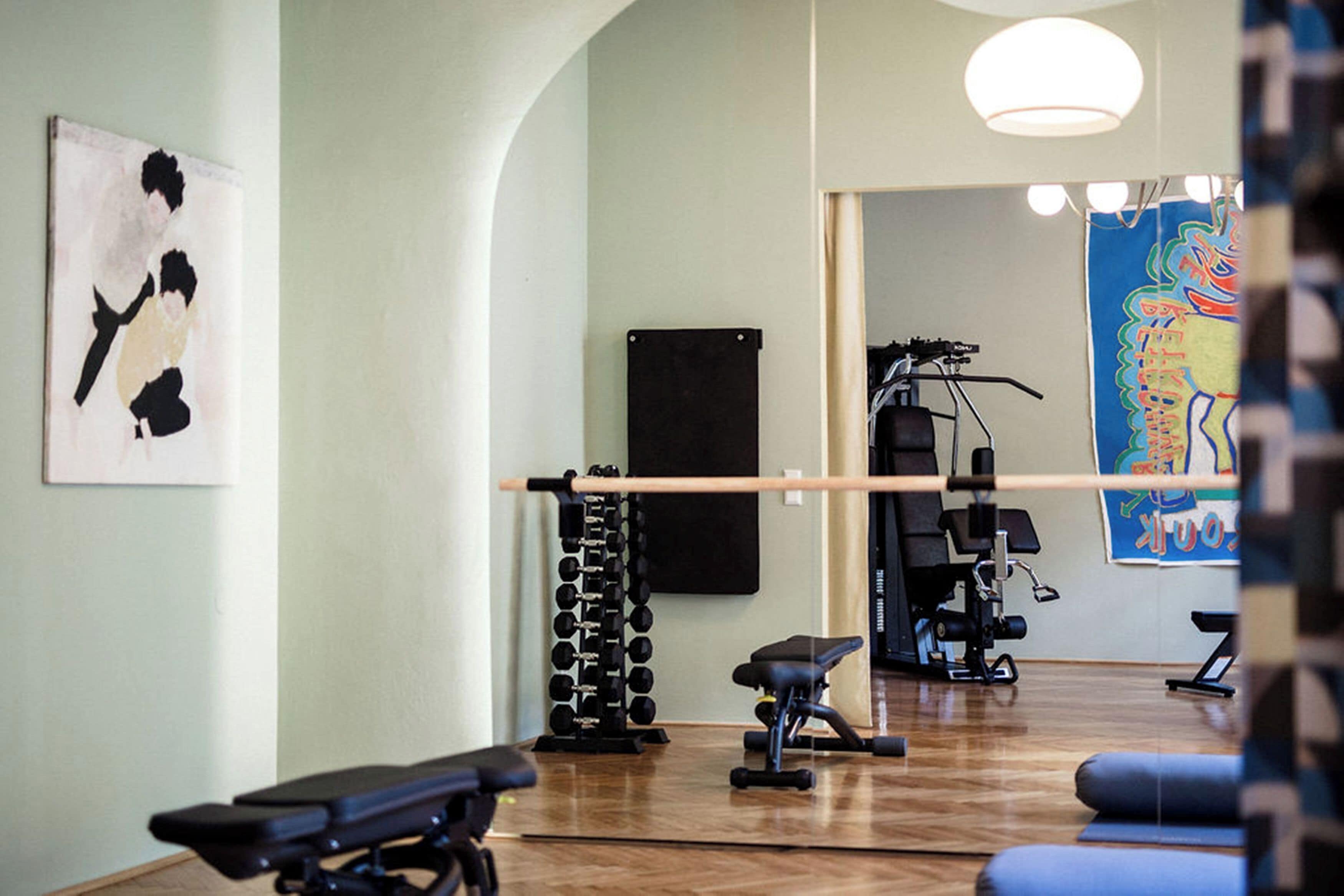 A gym with exercise equipment, a mirror, and a wall with a painting.