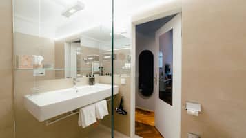 Un baño moderno con cabina de ducha de vidrio, un lavamanos blanco y un inodoro.