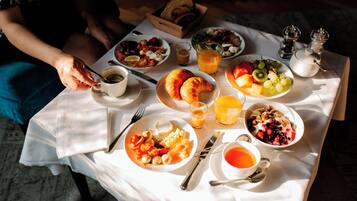 A breakfast table with various dishes, including croissants, fruit, and beverages.