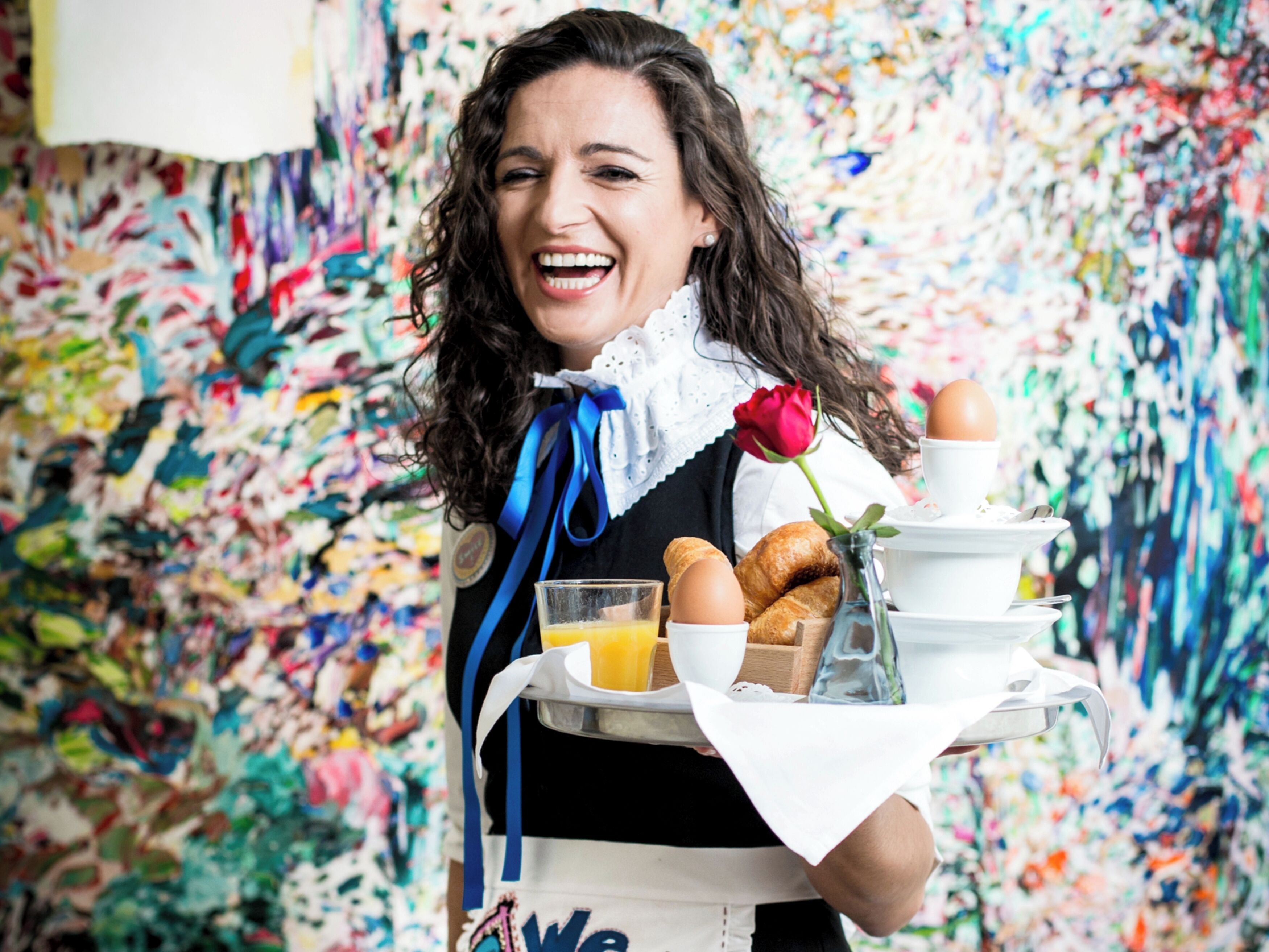 A person holding a tray with food items and a rose.
