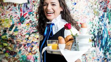 A person holding a tray with food items and a rose.
