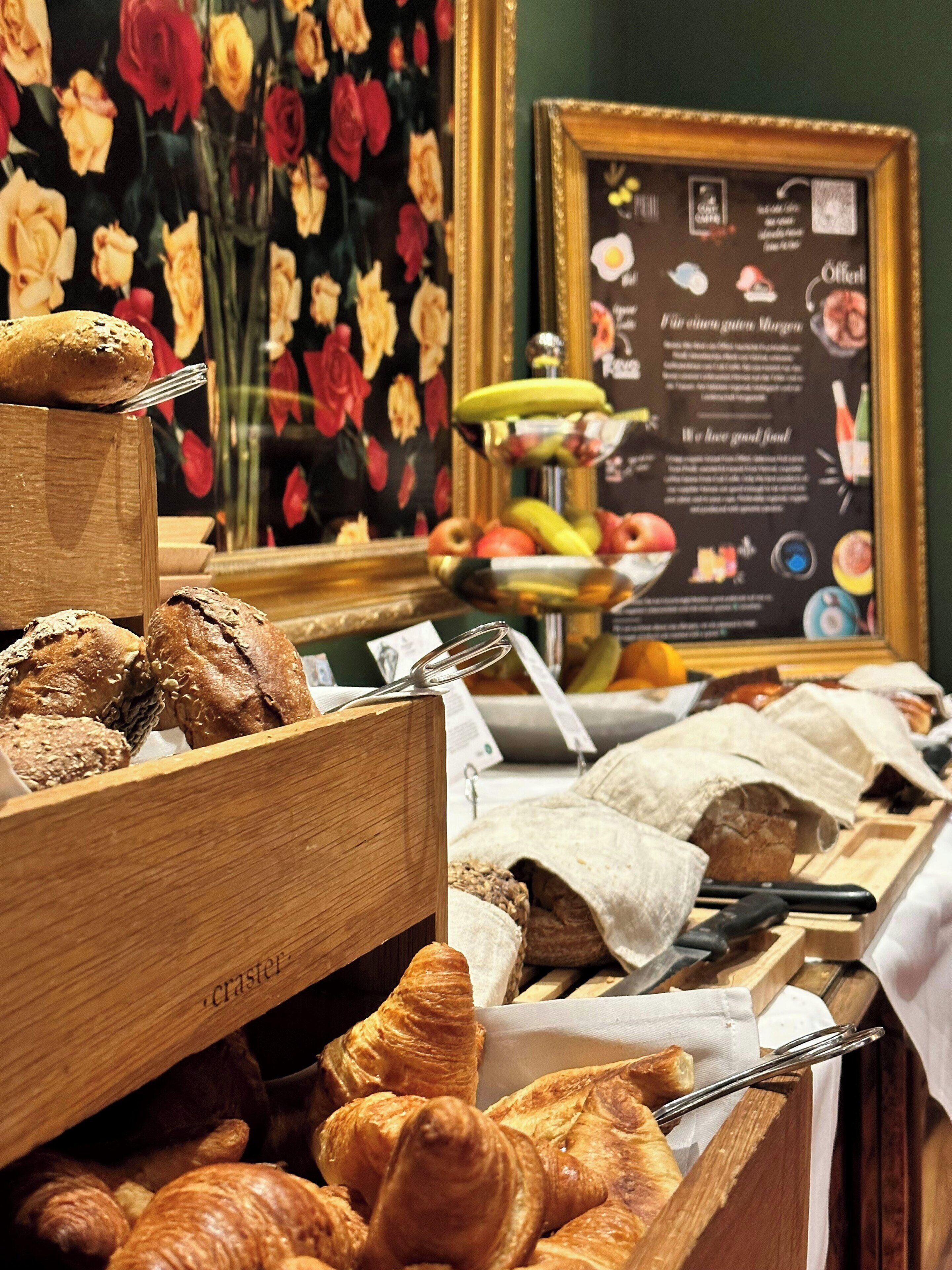 A bakery display with various baked goods, a framed menu, and a floral backdrop.