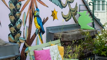 Een muurschildering met een ontwerp van een vogel en planten op een gevel.