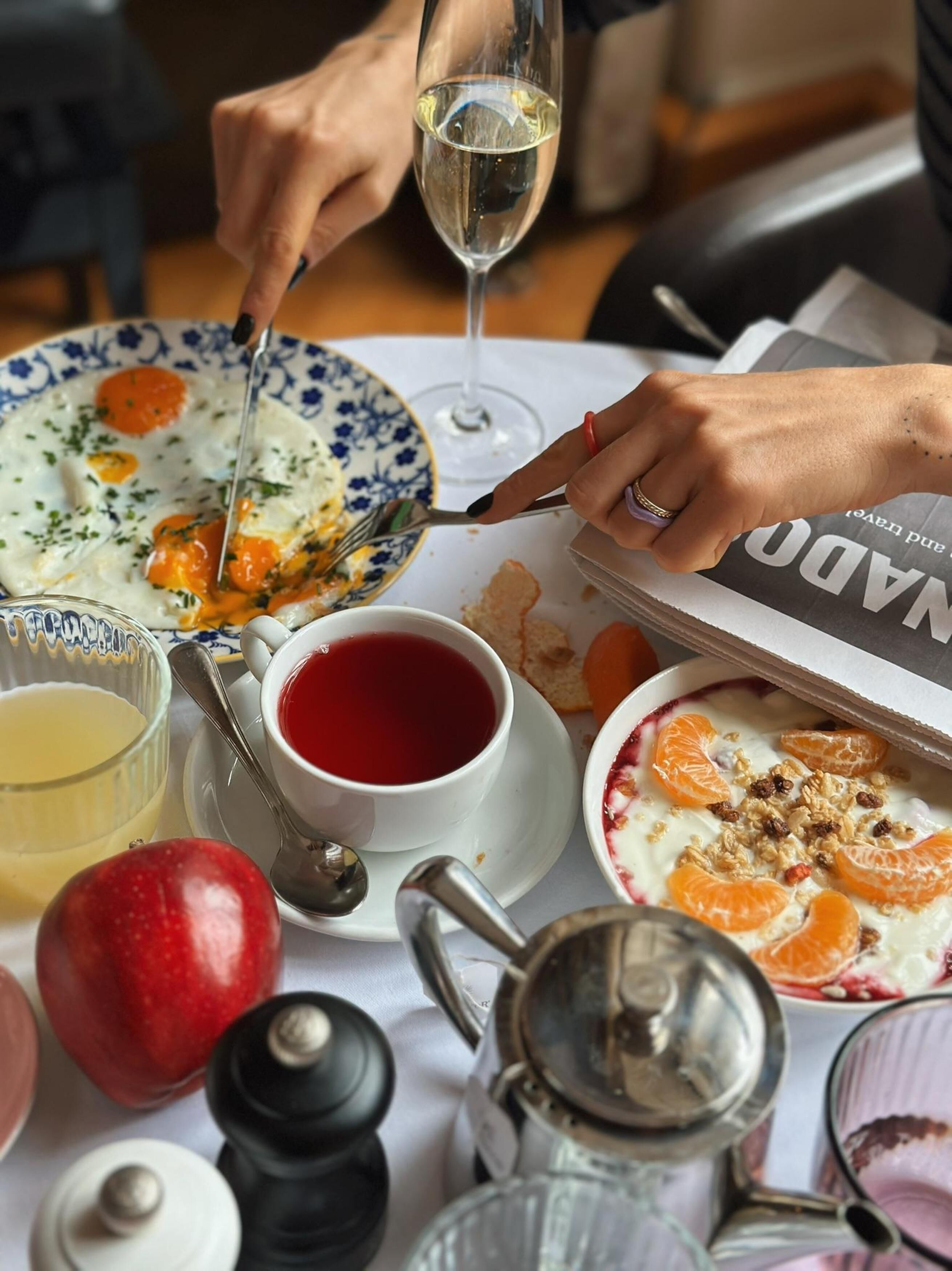 Una mesa de comedor con un plato de comida, una copa de vino, una taza de té y diferentes condimentos.