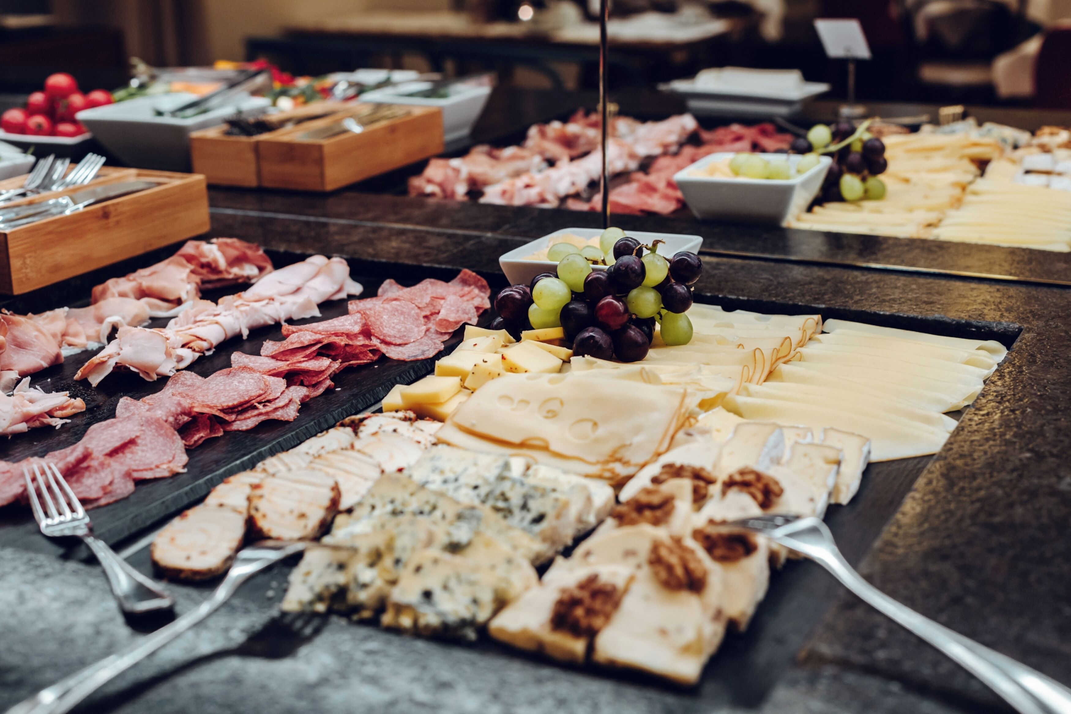 A buffet with various meats, cheeses, and fruits.
