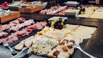 A buffet with various meats, cheeses, and fruits.
