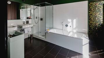 A modern bathroom with a glass-enclosed shower, a large bathtub, and a vanity with a mirror.