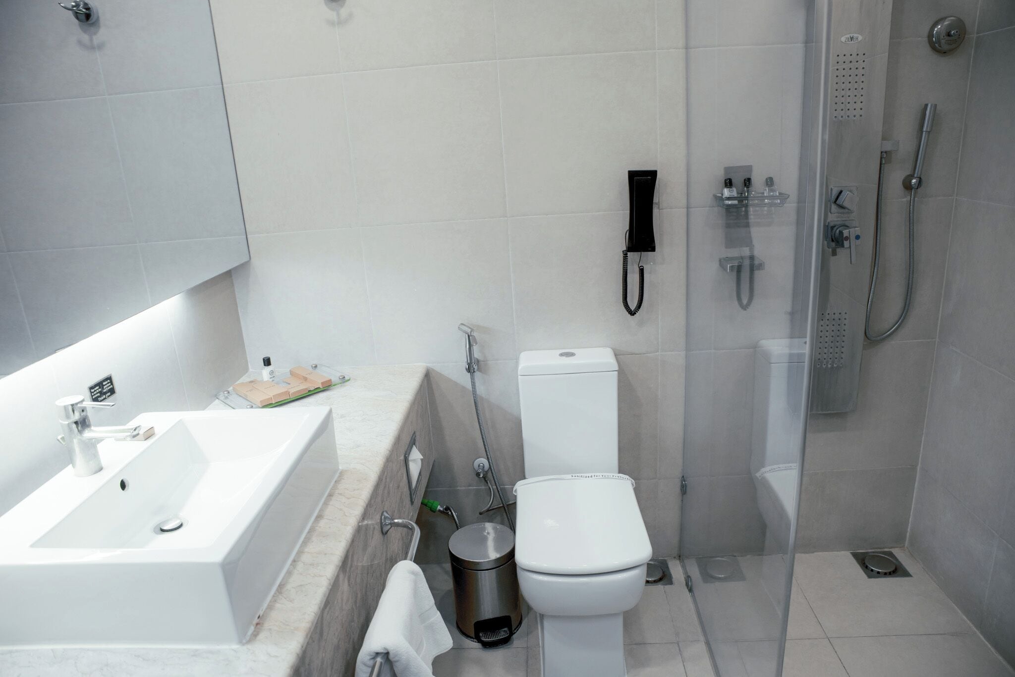 Un baño moderno con lavamanos, inodoro y ducha blancos.