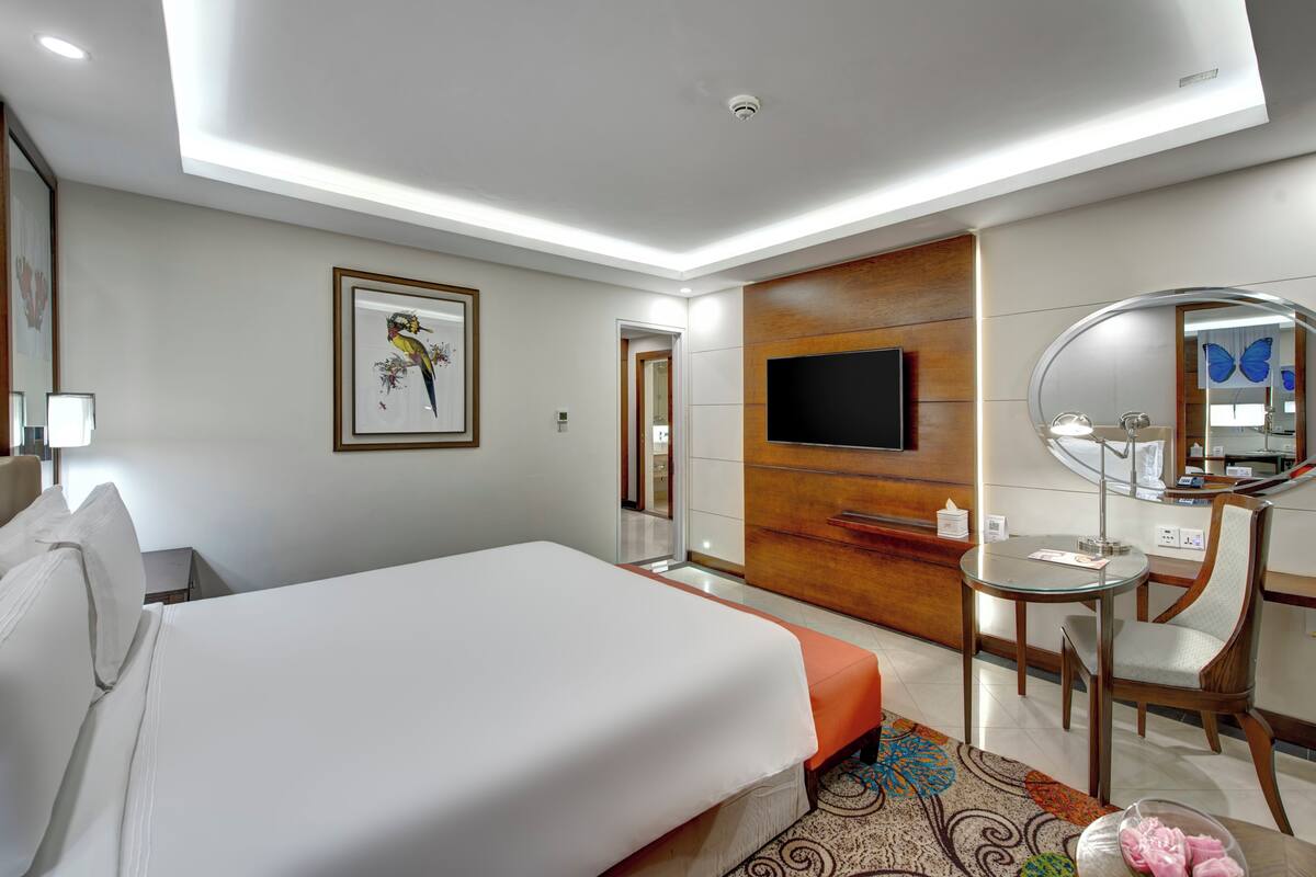 Une chambre d’hôtel comprenant un lit, un bureau avec une chaise, une télévision et un miroir.