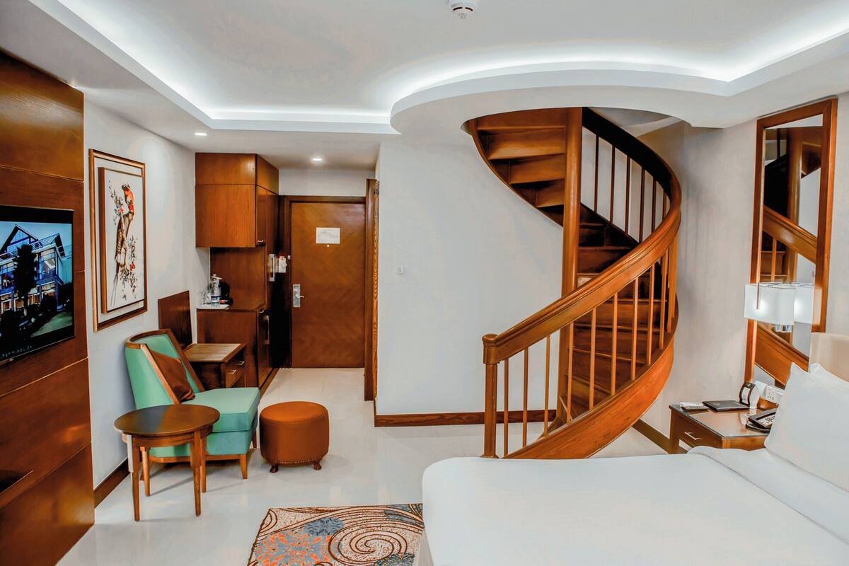 Un salon moderne avec un escalier en colimaçon, des meubles en bois et un téléviseur fixé au mur.