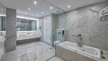 Un baño moderno con ducha envuelta en vidrio, una bañera amplia y un lavamanos con espejo.