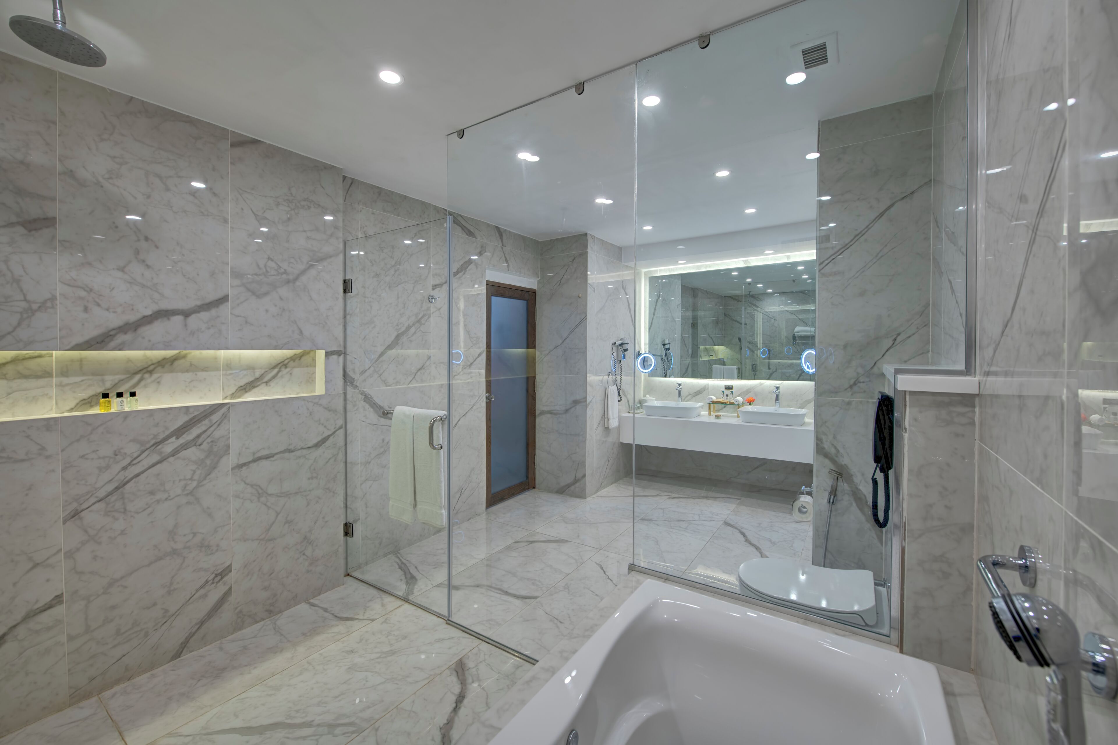 A modern bathroom with a glass-enclosed shower, a white bathtub, and a large mirror above the sink.