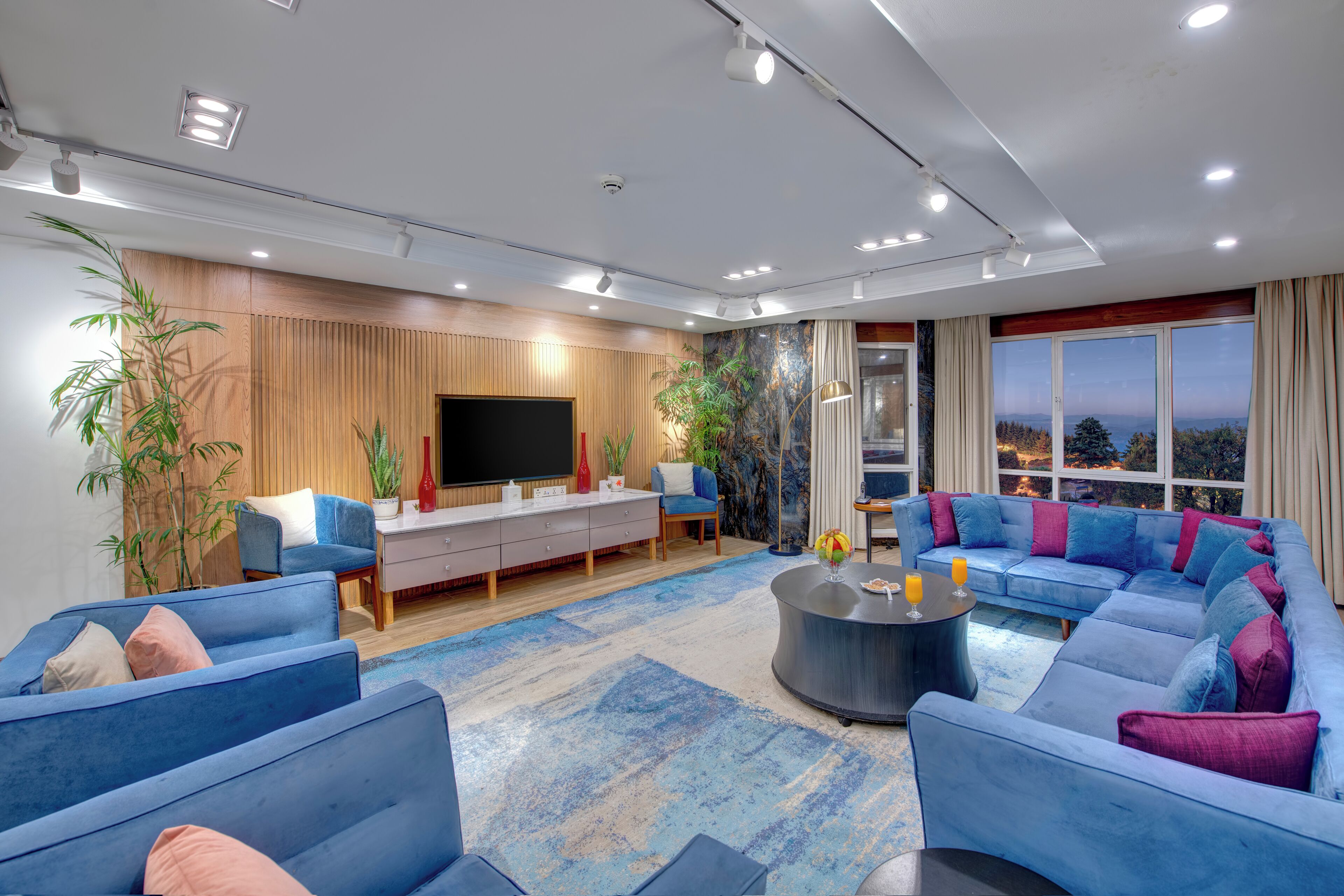 Una sala de estar moderna con un sofá modular, un televisor de pantalla plana y un amplio ventanal con vistas.