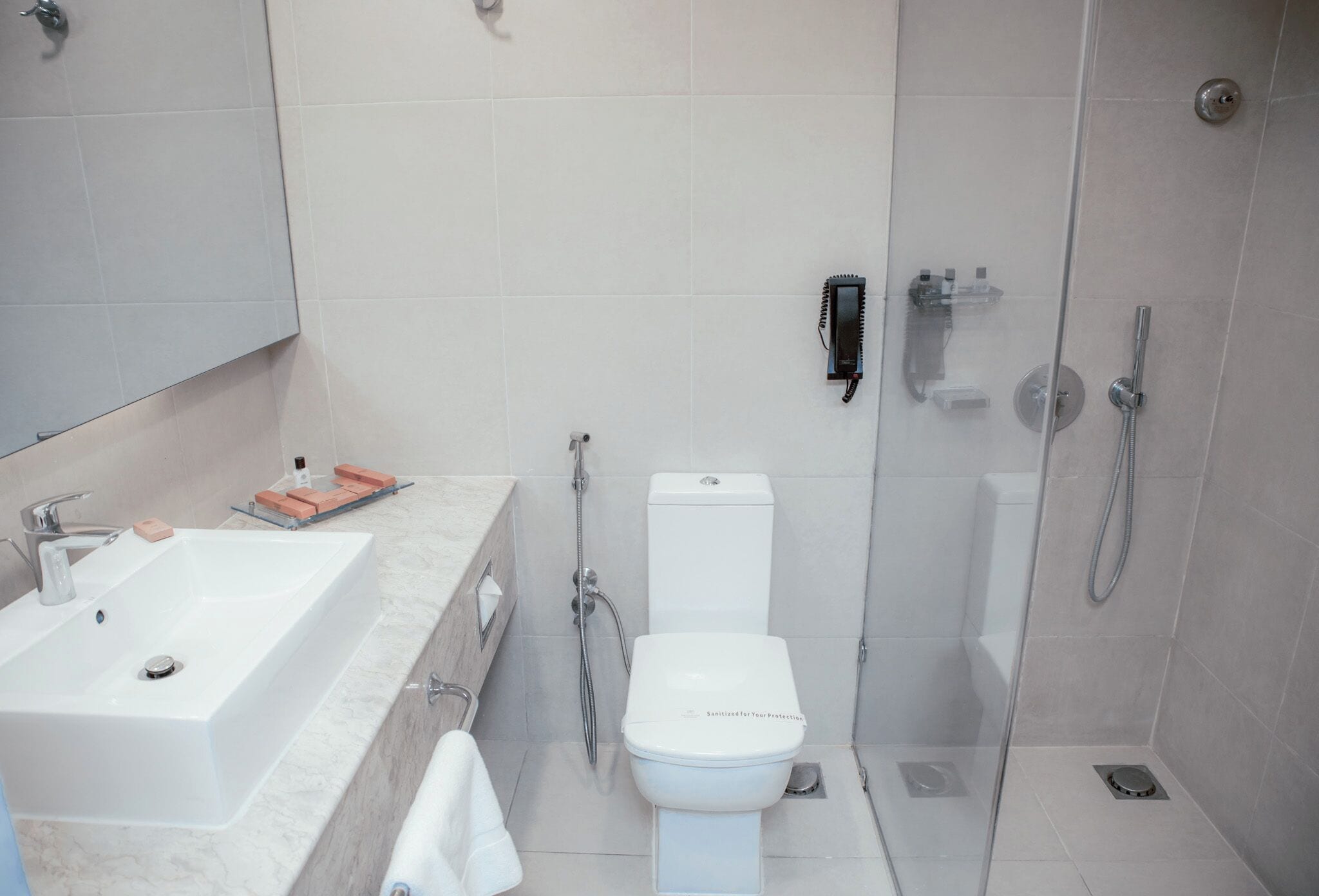 Une salle de bain moderne équipée d’un lavabo, de toilettes et d’une douche.