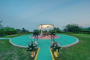 Een rond buitengebied met een centrale zithoek, omgeven door groen en wandelpaden.