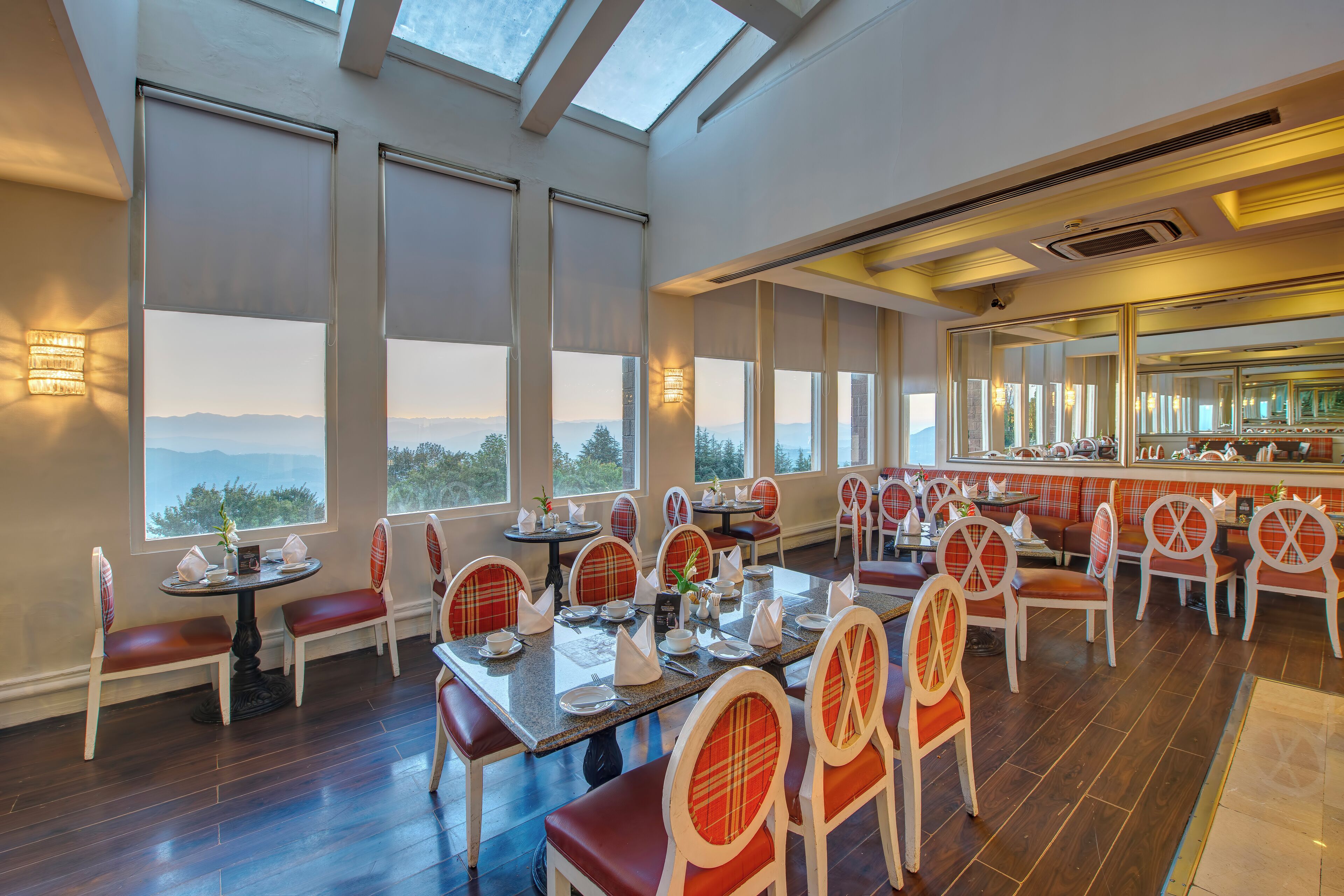 A restaurant with high ceilings, large windows, and a view of the mountains.