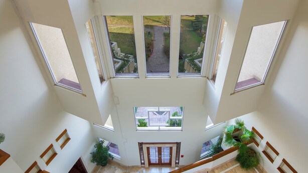 A high-ceilinged interior with multiple large windows offering views of a mountainous landscape.