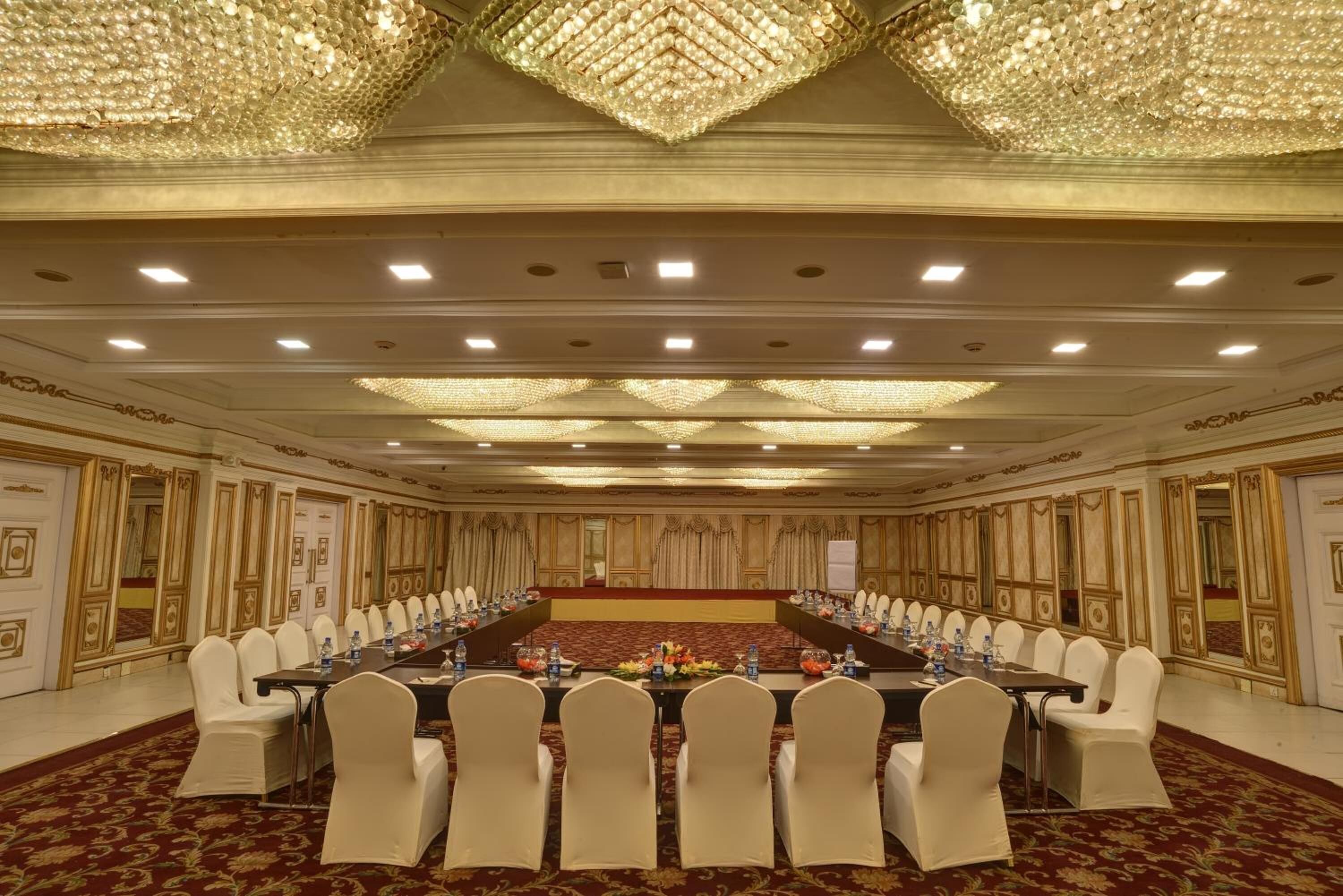 A conference room with a long table, white chairs, and a chandelier.