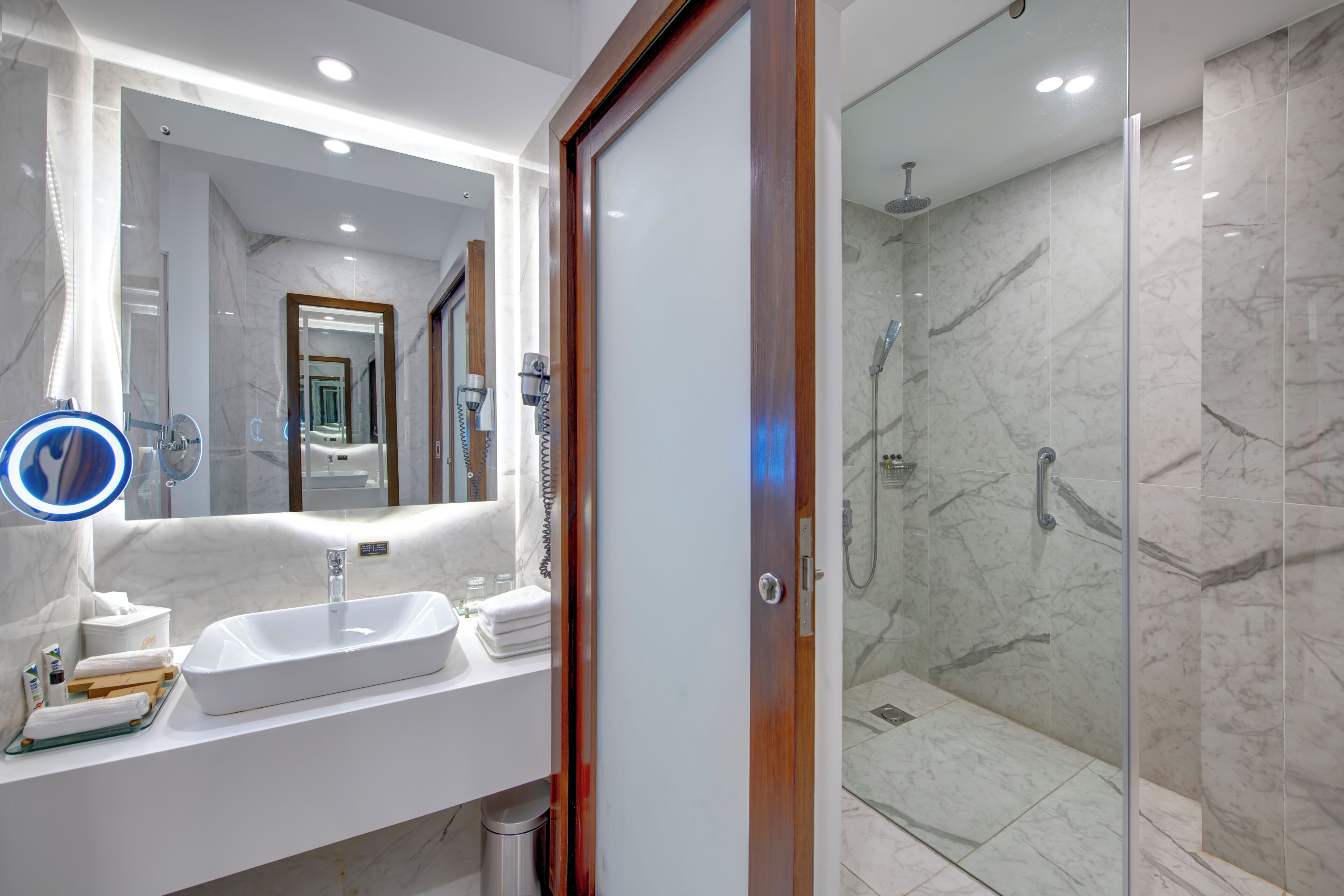 Un baño moderno con lavamanos, espejo y ducha blancos.