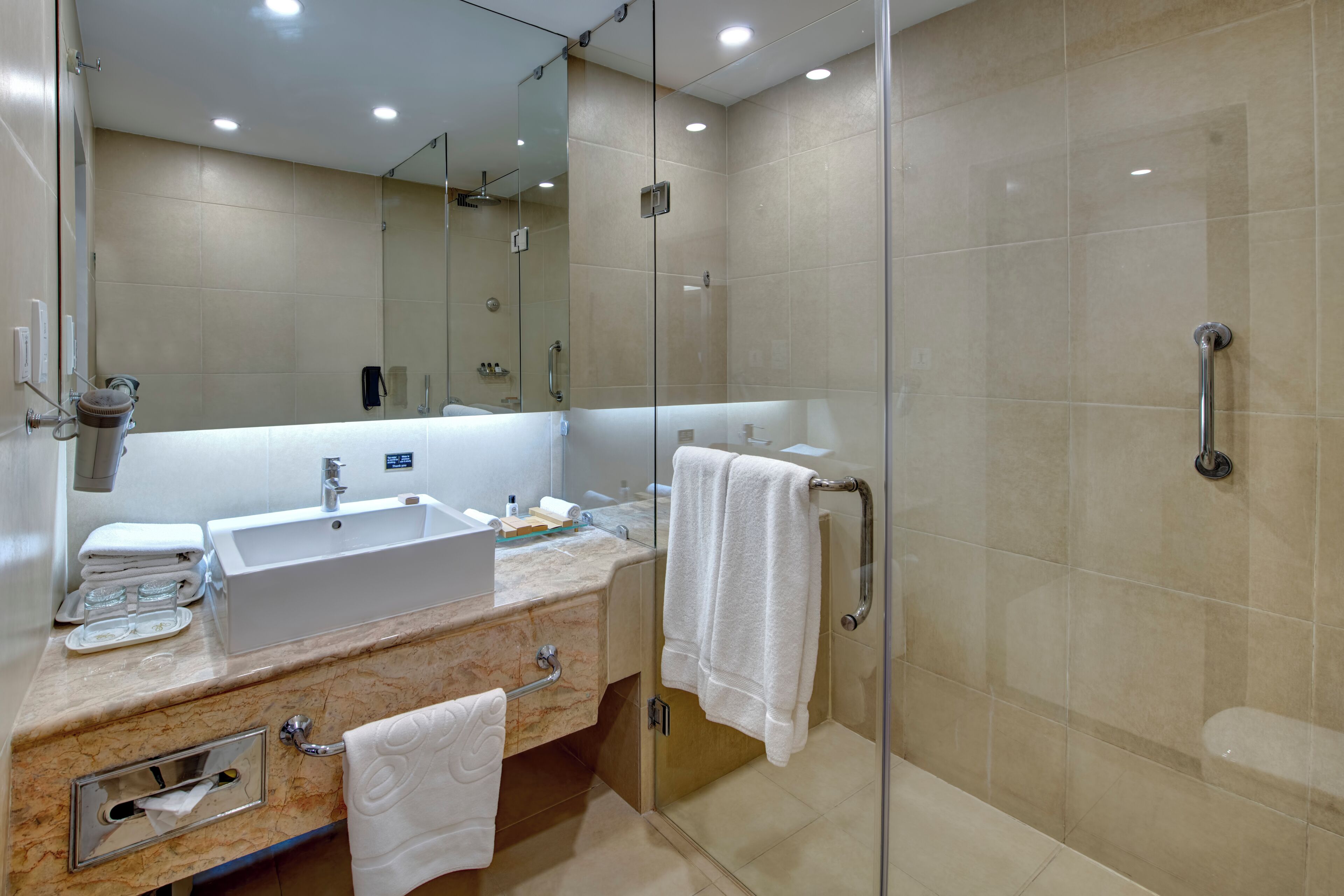 A modern bathroom with a glass-enclosed shower, a sink with a marble countertop, and a large mirror.