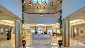 A spacious lobby with a marble floor, a reception desk, and a chandelier.
