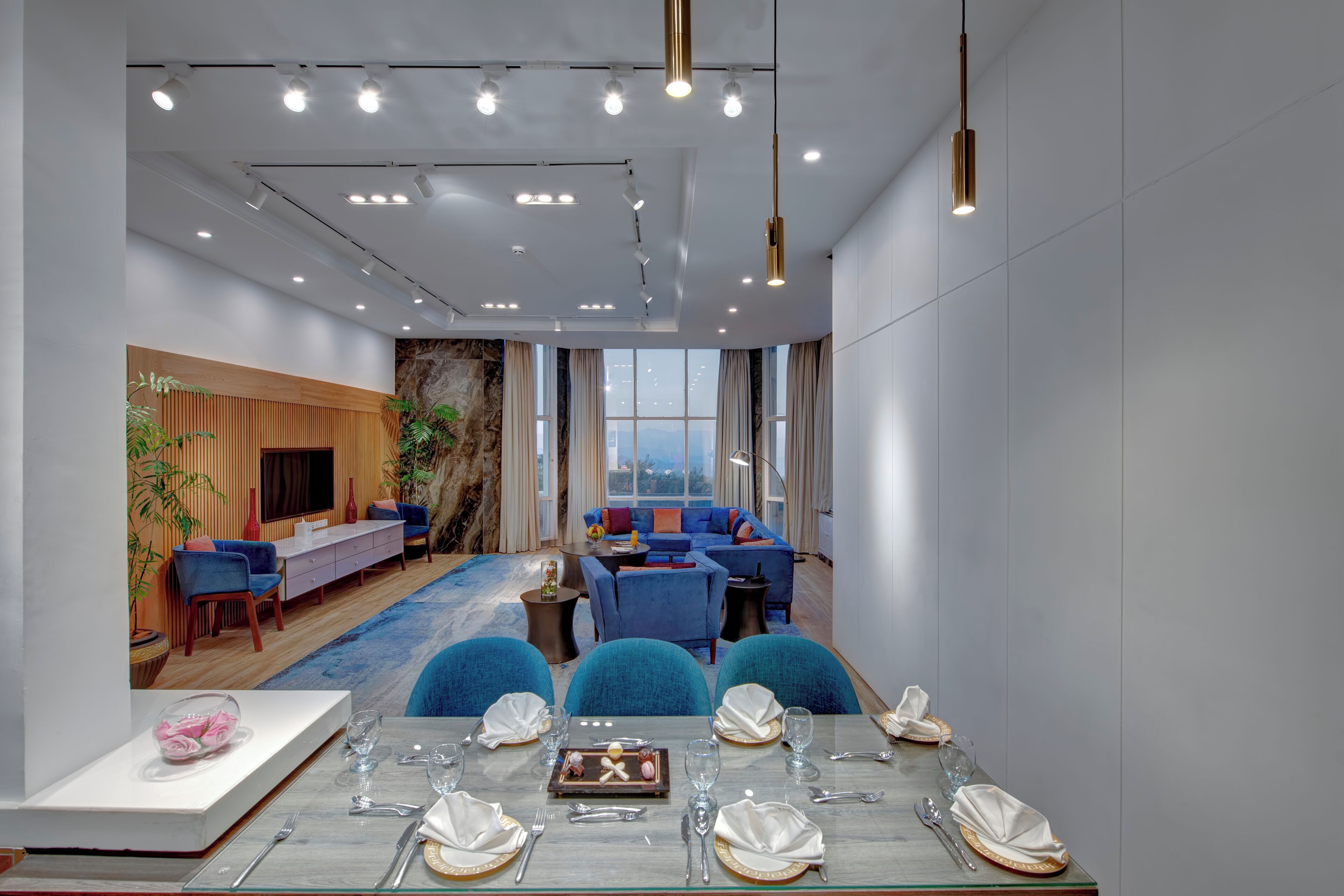 Una habitación de hotel moderna con zona de comedor, asientos y un ventanal grande.