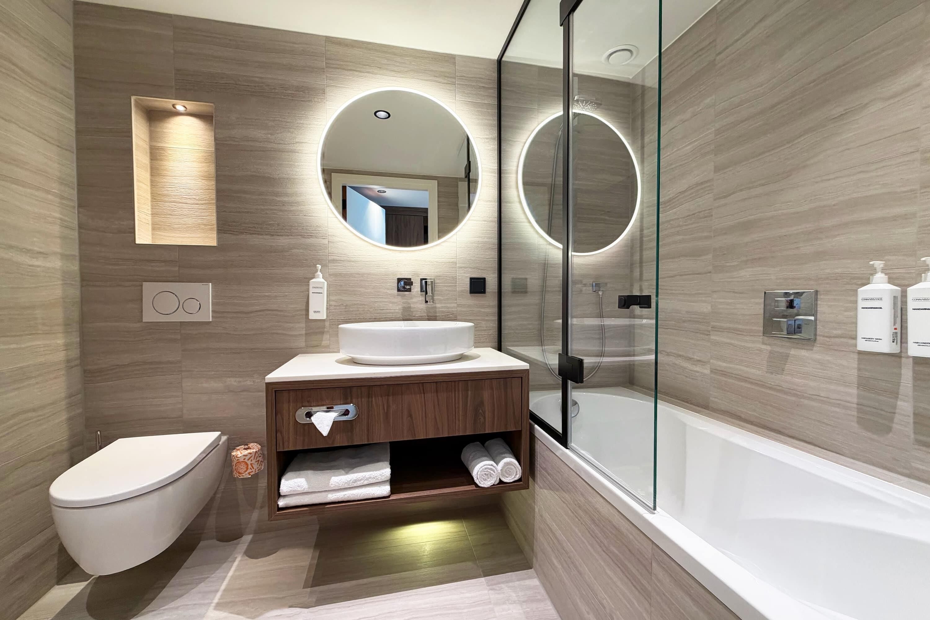 A modern bathroom with a toilet, sink, and bathtub.