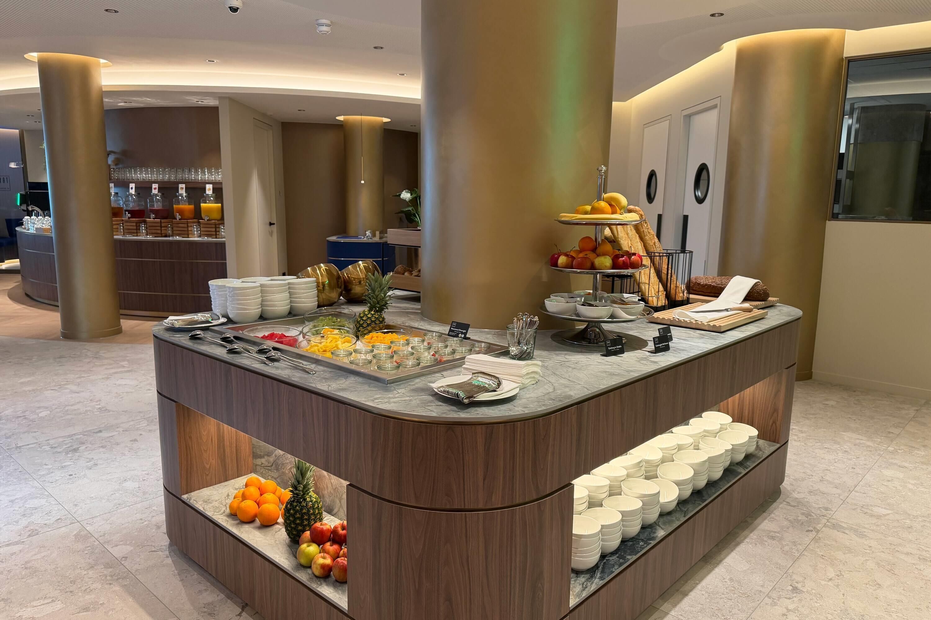 A buffet area with a variety of fruits, a fruit display, and a beverage station.