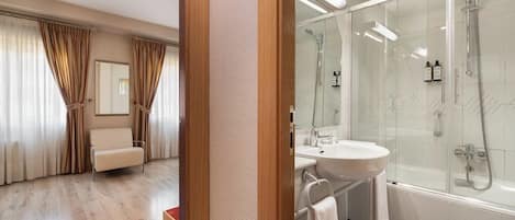 A modern bathroom with a glass-enclosed shower, a white sink, and a toilet.