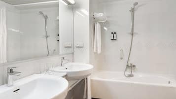 A modern bathroom with two sinks, a bathtub, and a shower.