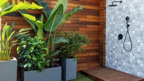 Une salle de bain moderne avec un mur en bois, une douche carrelée avec des motifs et des plantes en pot.
