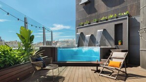 A rooftop pool area with a view of the city, a waterfall feature, and seating arrangements. - Renaissance Barcelona Hotel (Barcelona)