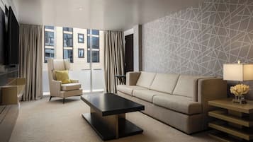 A modern living room with a sofa, armchair, and coffee table, large windows with curtains, and a geometric-patterned wall.