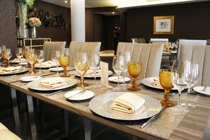 A dining table set with plates, glasses, and cutlery, with a vase of flowers on the left. - Renaissance Panama City Hotel  (Panama City)