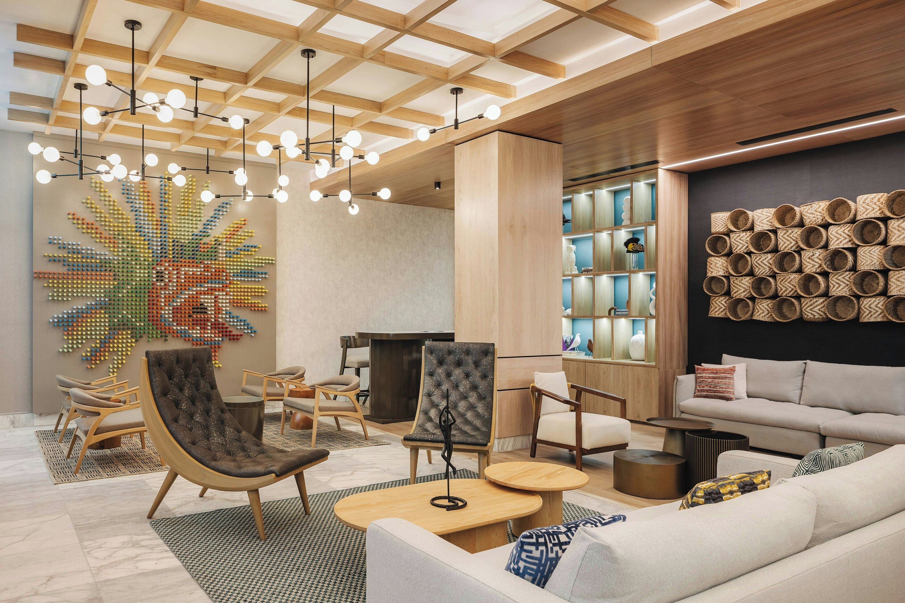 A modern interior with a wooden ceiling, a colorful abstract wall art, and a seating area with sofas and chairs.