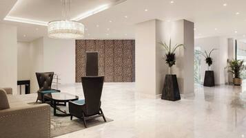 A modern lobby with a chandelier, seating area, and decorative plants.