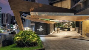 Una entrada de hotel moderna con un llamativo letrero 'Renaissance Hotel', un área exterior bien iluminada con una estructura de madera y una escalera que lleva a los pisos superiores.