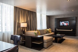 A modern hotel room with a sofa, a coffee table, a TV mounted on the wall, and a dining area with a table and chairs. - Renaissance Panama City Hotel  (Panama City)