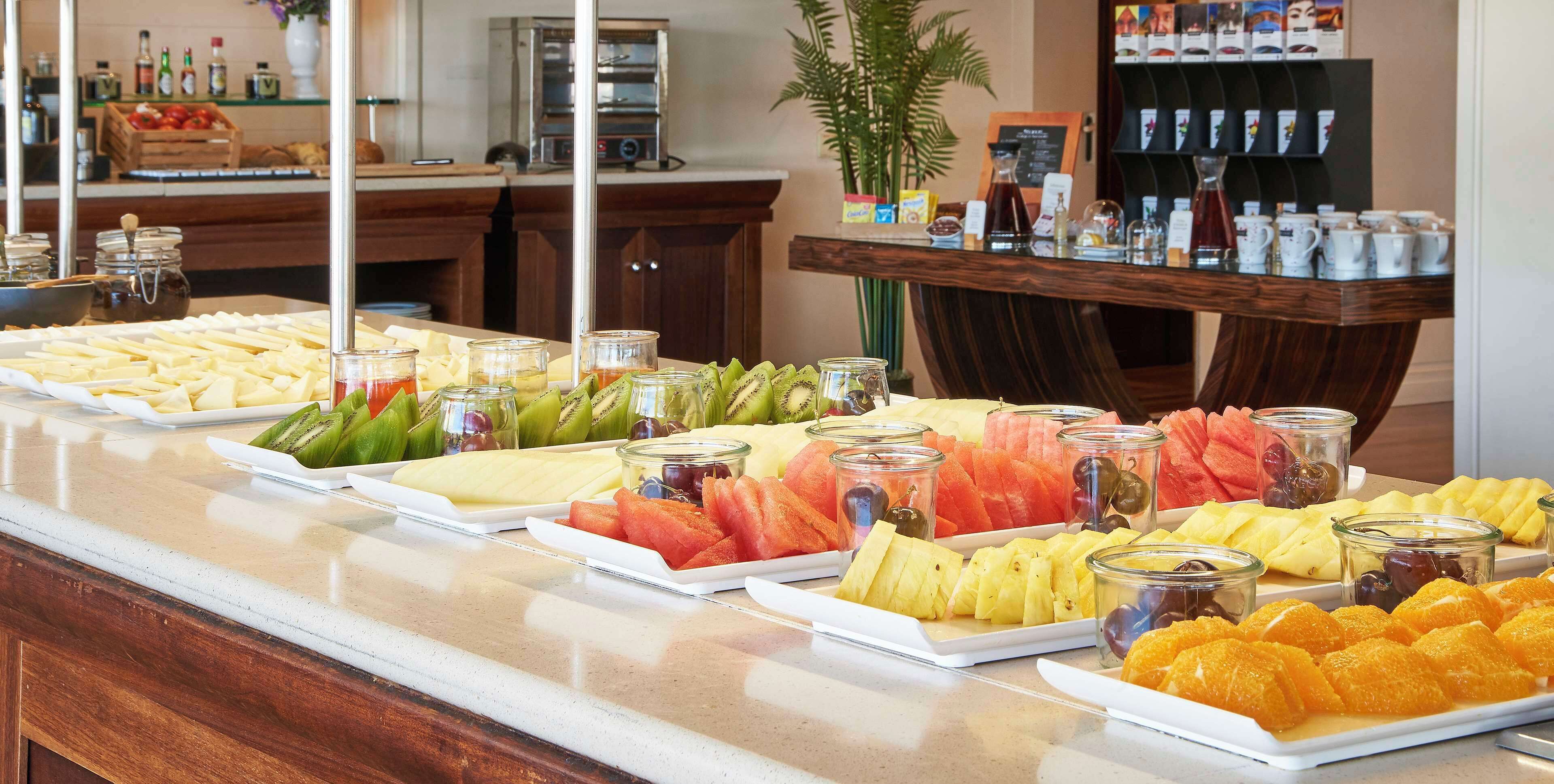 A buffet with various fruits and cheeses.