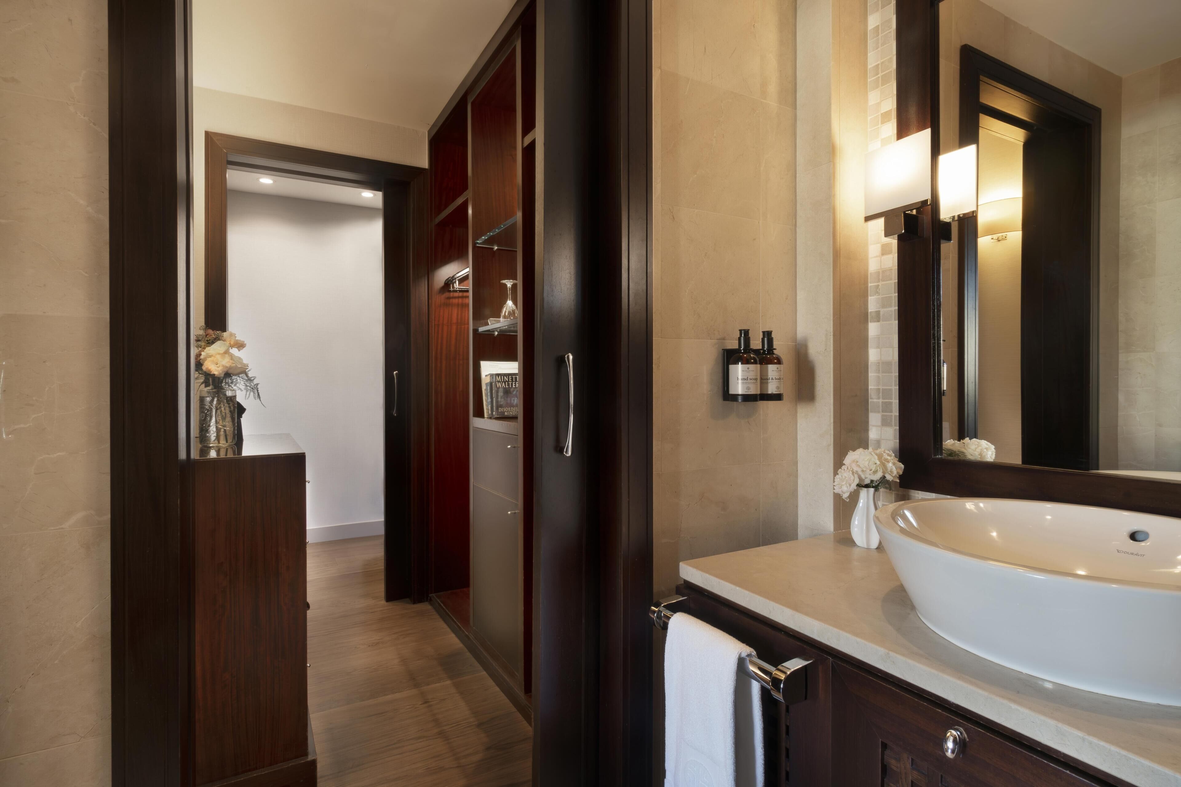 Un baño moderno con una bañera independiente grande, un espejo y un mueble de tocador con un perchero.