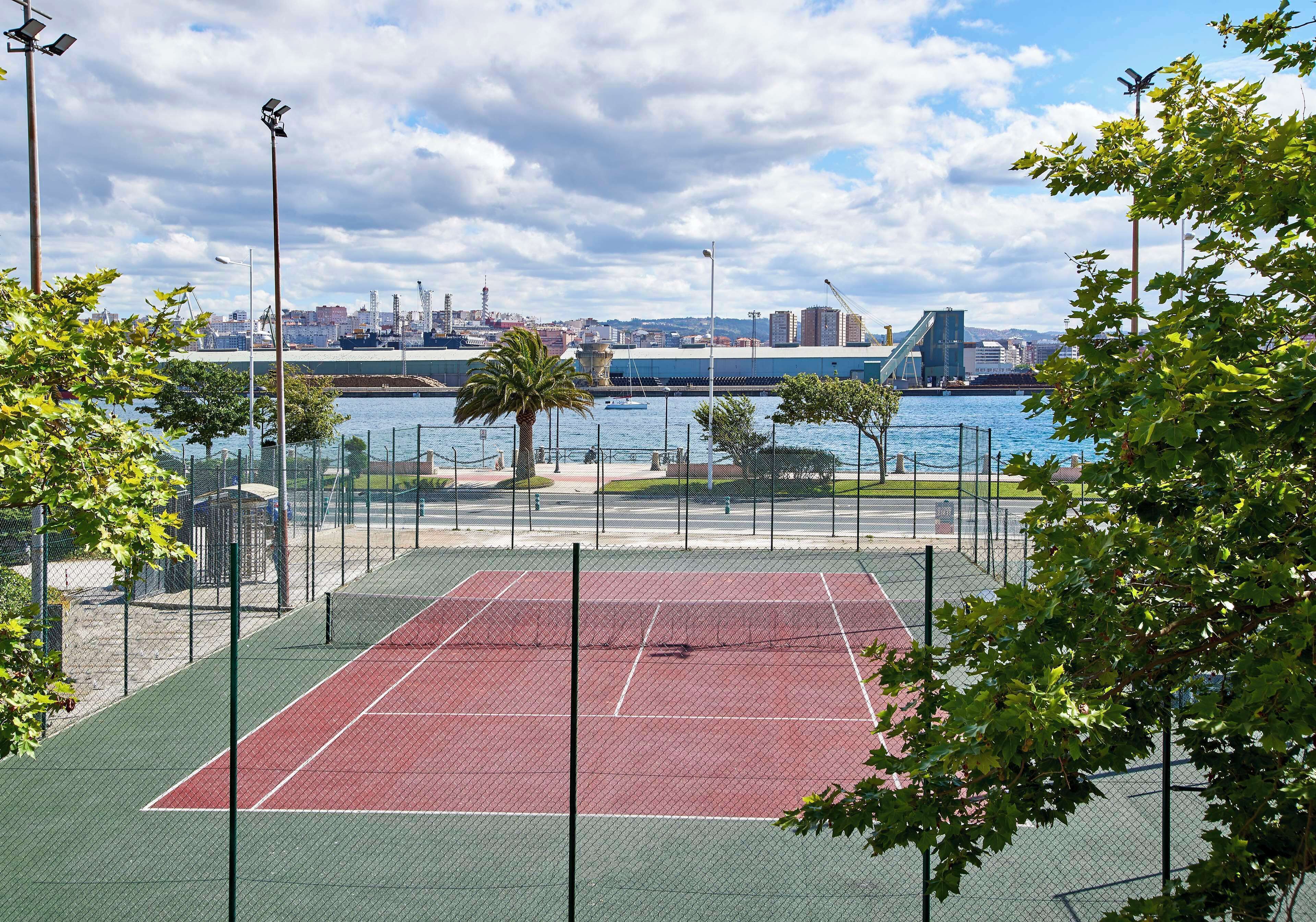 An outdoor tennis court with a city skyline in the background.