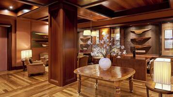 Un hall con suelo de madera, una recepción, un jarrón con flores y una lámpara.
