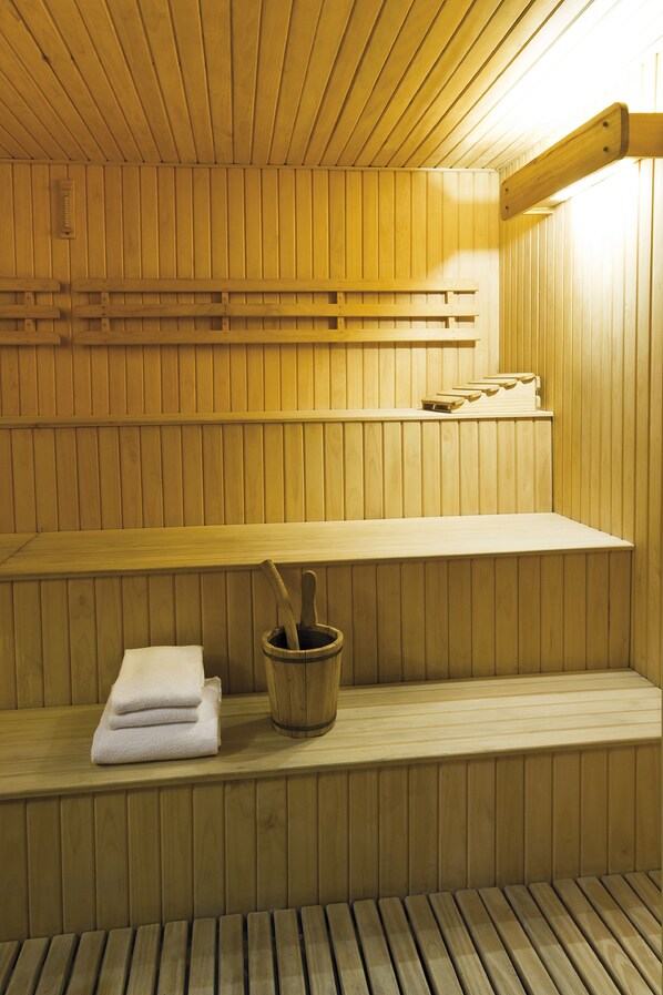 Una sauna de madera con bancos y un balde de madera.
