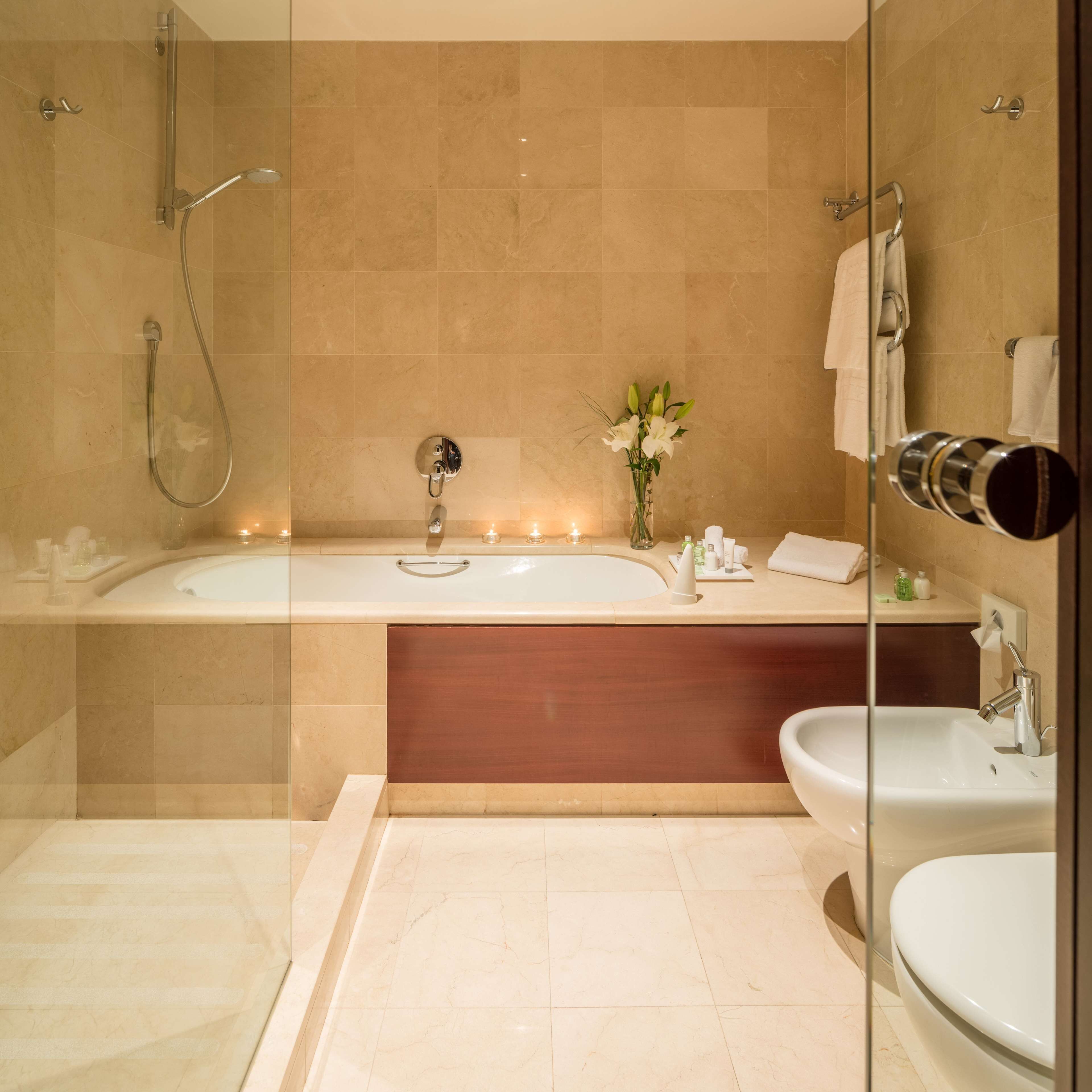 Un baño moderno con ducha acristalada, una bañera amplia, un tocador con espejo y un lavamanos.