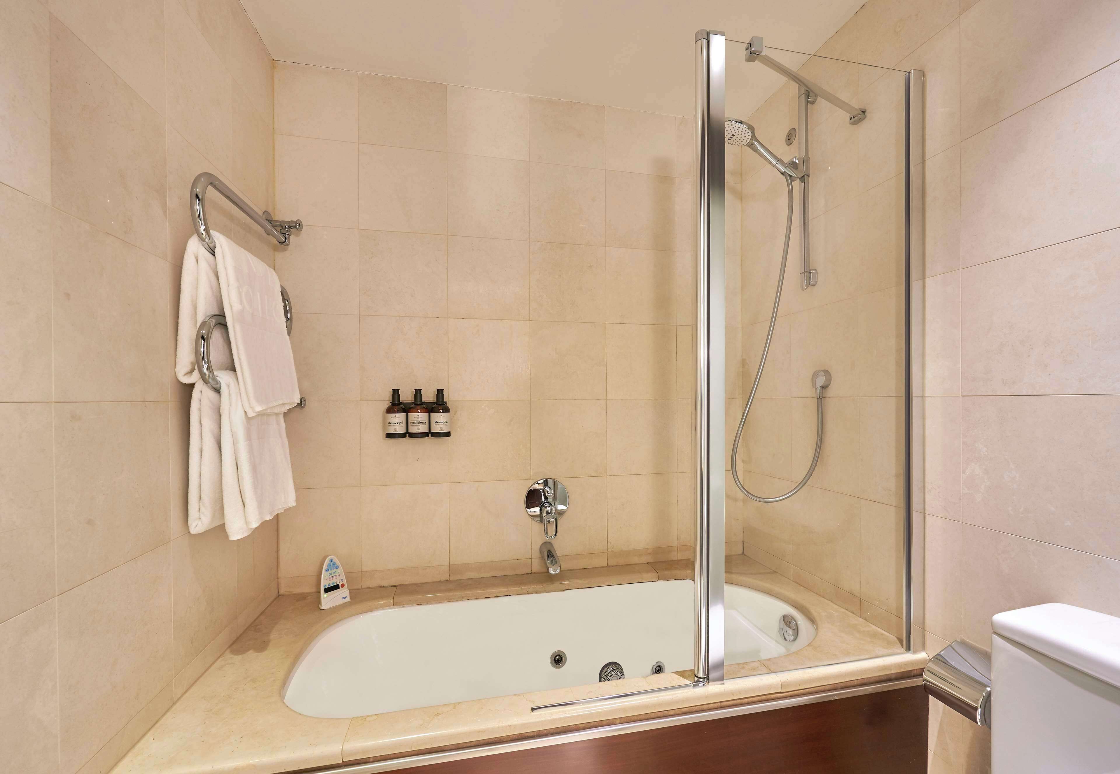Un baño moderno con ducha de vidrio, bañera y retrete.
