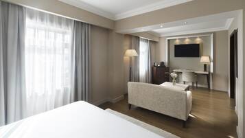 A hotel room with a large bed, a desk with a chair, a flat-screen TV, and a wardrobe.