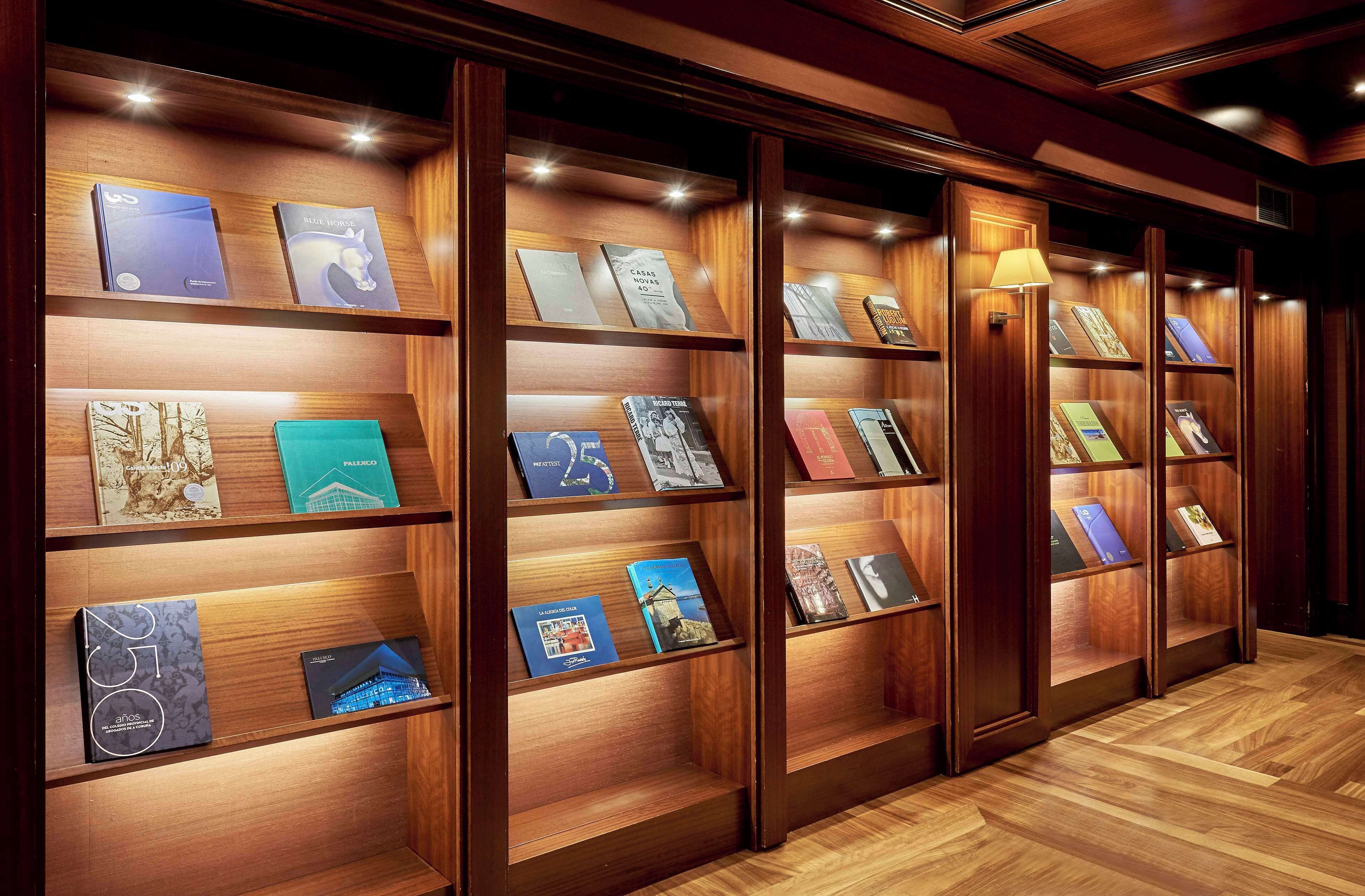 A row of wooden bookshelves with illuminated books and a lamp.