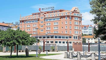 A multi-story hotel with a red facade, multiple windows, and a sign reading "NH COLLECTION HOTELS".